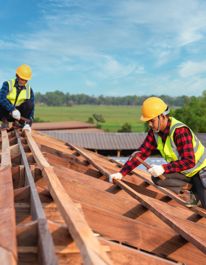 Jobs - Zwei Dachdecker arbeiten mit Sicherheitshelm und warnweste auf dem Dach